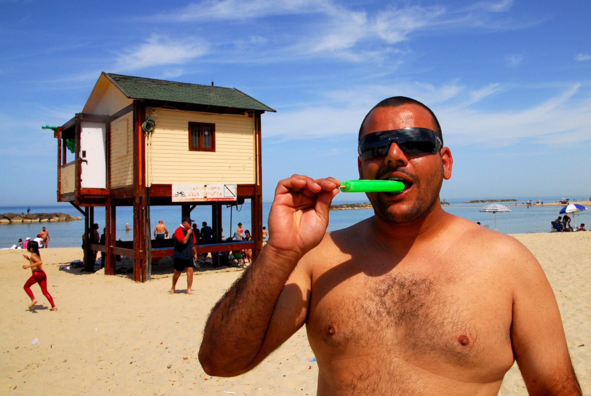 Israeli man eating a cold ice pop on hot hit wave day