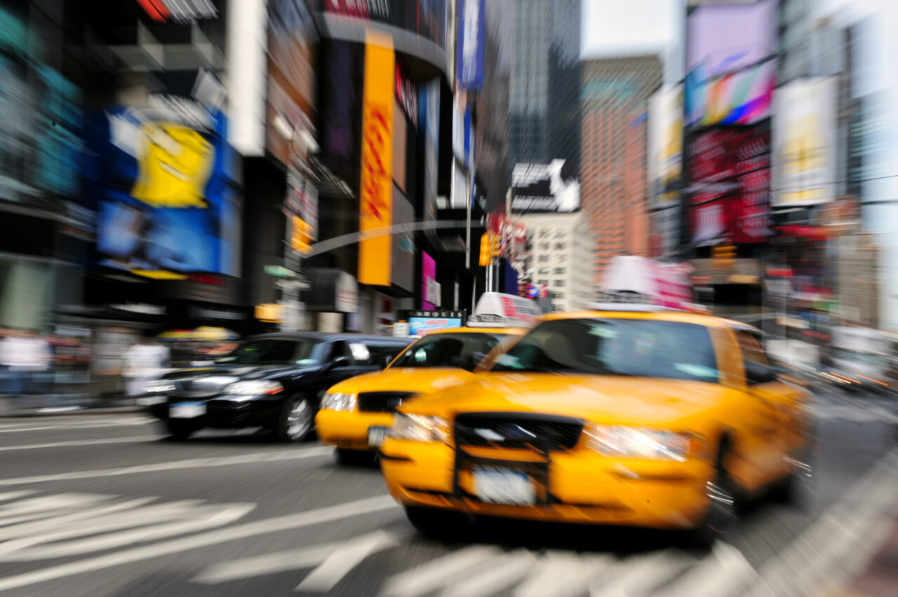 Motion blur photo of yellow taxi cabs rushing on Broadway road in Times Square during rush hour in midtown Manhattan, New York City, New York USA