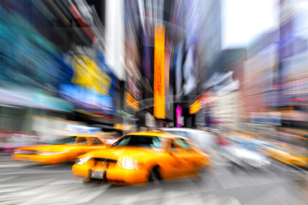 Motion blur photo of yellow taxi cabs rushing on Broadway road in Times Square during rush hour in midtown Manhattan, New York City, New York USA.Colorful abstract background. No people. Copy space