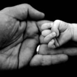 Fathers hand holding a newborn baby girl hand