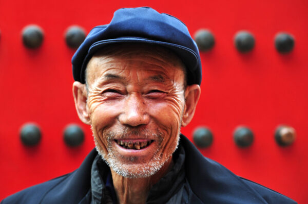 Portrait of a happy active senior adult Chinese man visiting at the Forbidden City in Beijing, China.