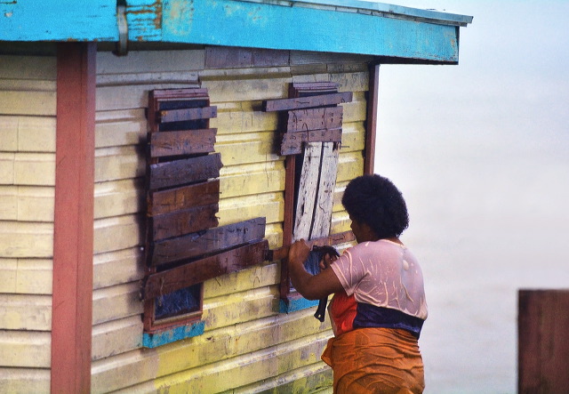 Fijian woman boarding up her house during a Tropical Cyclone