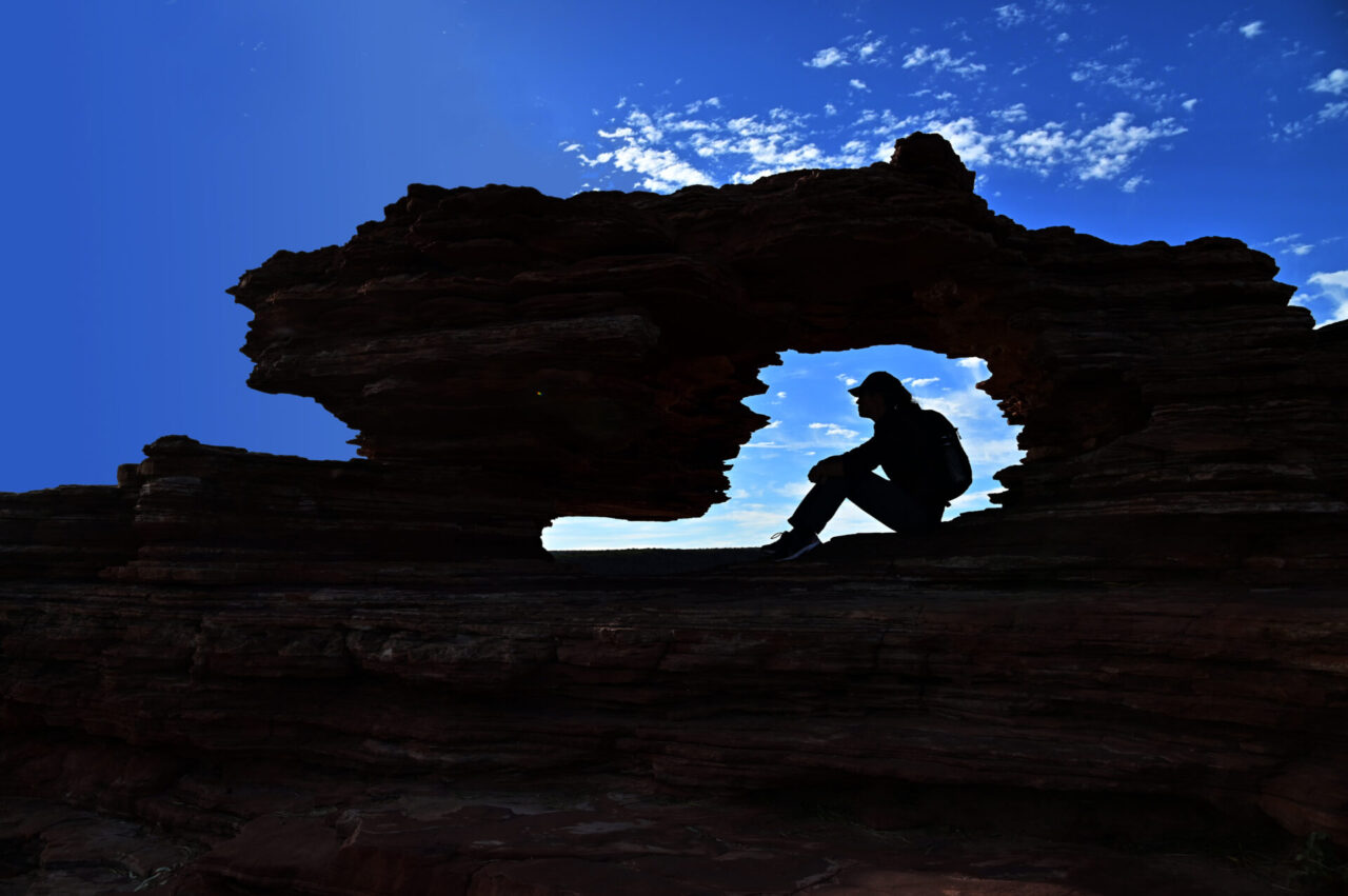 Silhouette of Australian female hiker resting inside Nature's Window. Kalbarri National Park Western Australia