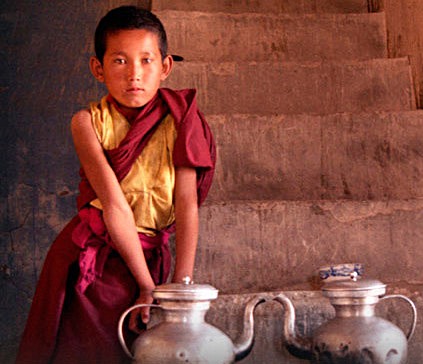 Young Tibetan monk serve a tea boy in a monastery