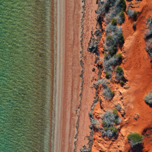 Aerial drone landscape view of coastal sea shore red cliffs and turquoise water environment at Peron Peninsula in Shark Bay, Western Australia.