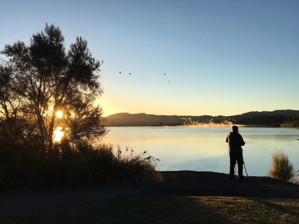 Nature and landscape photographer photographing at sunrise Lake Rotorua in the centre of the North Island of New Zealand.