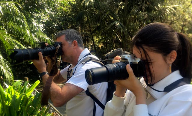 Professional documentary travel photographer teaching a young adult woman student photography outdoors