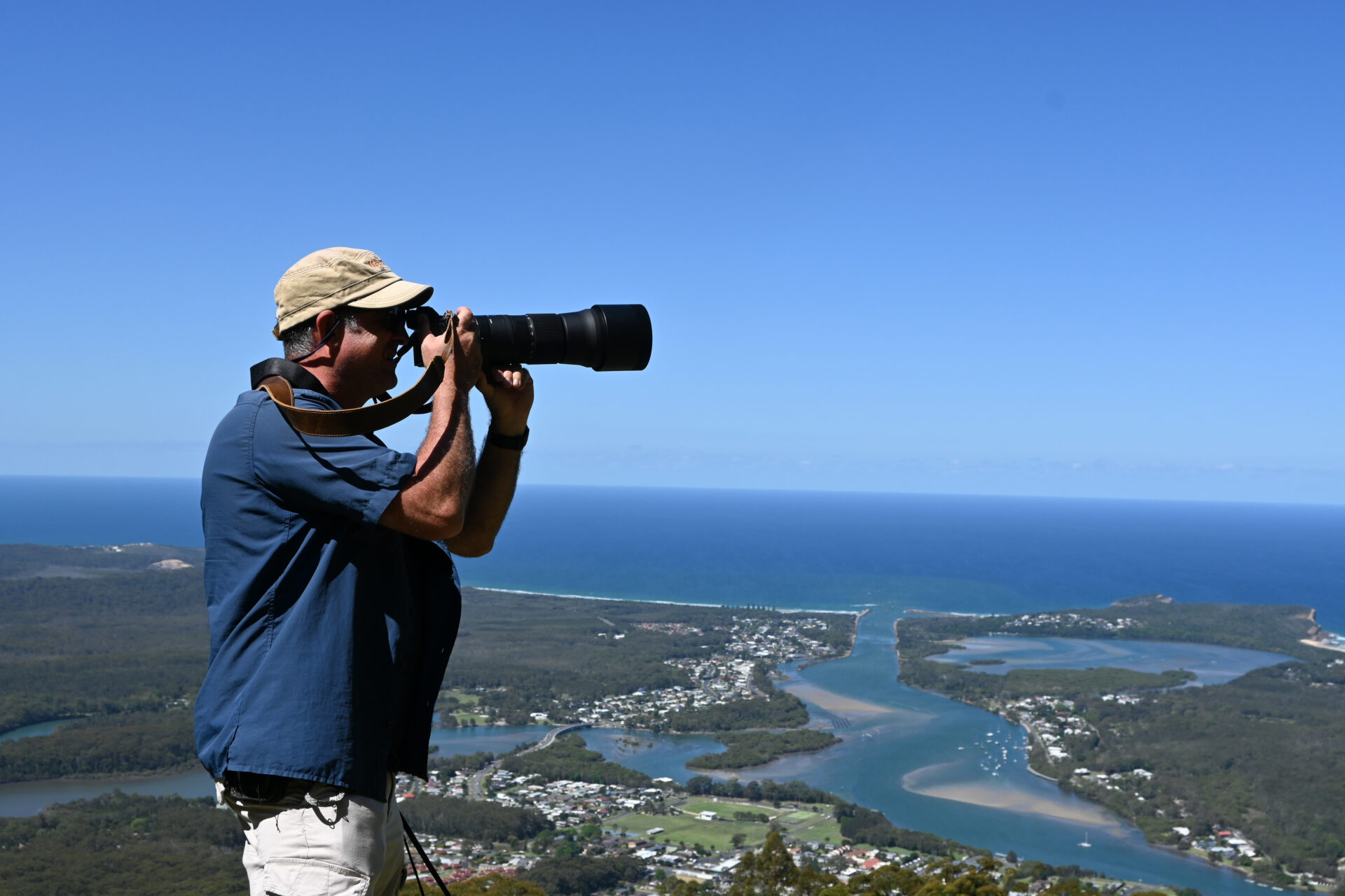 Documentary travel photographer is teaching a female student how to take an aerial landscape view photo of Camden Heaven River with a telephoto lens on a tripod in New South Wales, Australia